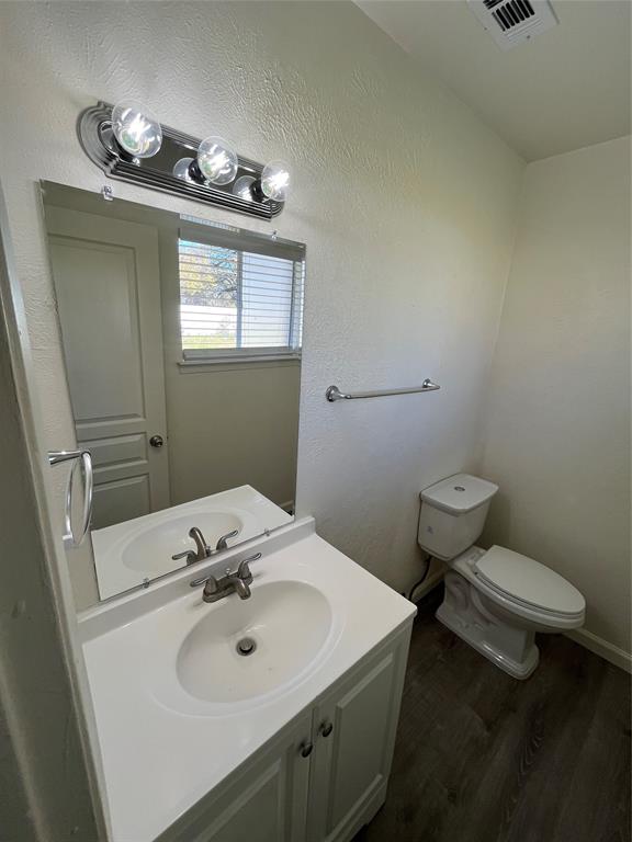 10135 Kittyhawk Lane Dallas, TX 75217 - Photo 9 of 17 Half bath with vanity, dark wood-style floors, and a textured wall