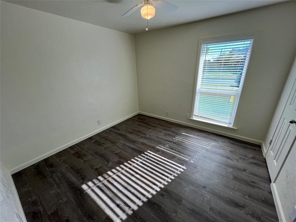 10135 Kittyhawk Lane Dallas, TX 75217 - Photo 10 of 17 Empty room featuring dark wood-type flooring and baseboards