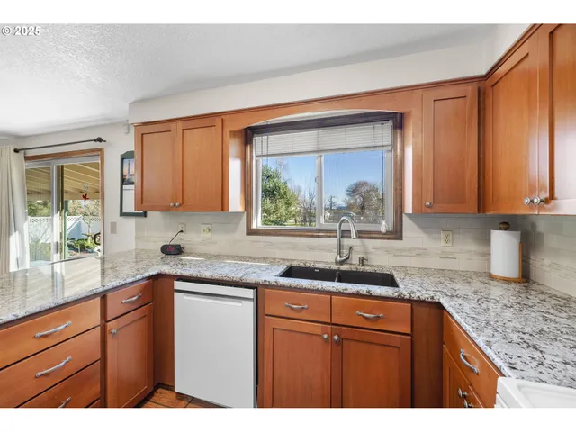 a kitchen with stainless steel appliances kitchen island granite countertop a table chairs and a refrigerator