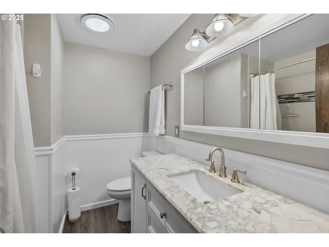 a bathroom with a granite countertop sink a mirror and shower