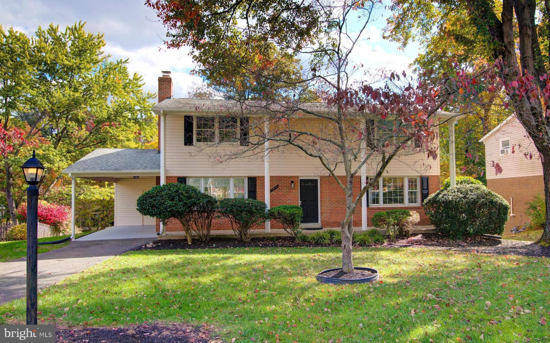 a front view of a house with a yard and a tree