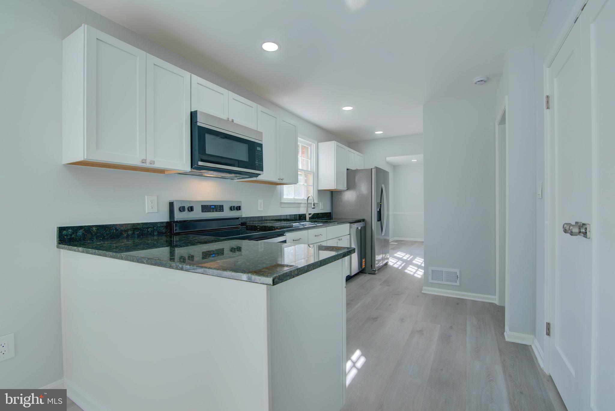 7411 Reservation Drive Springfield, VA 22153 - Photo 3 of 30 a kitchen with stainless steel appliances granite countertop a stove a sink and a microwave