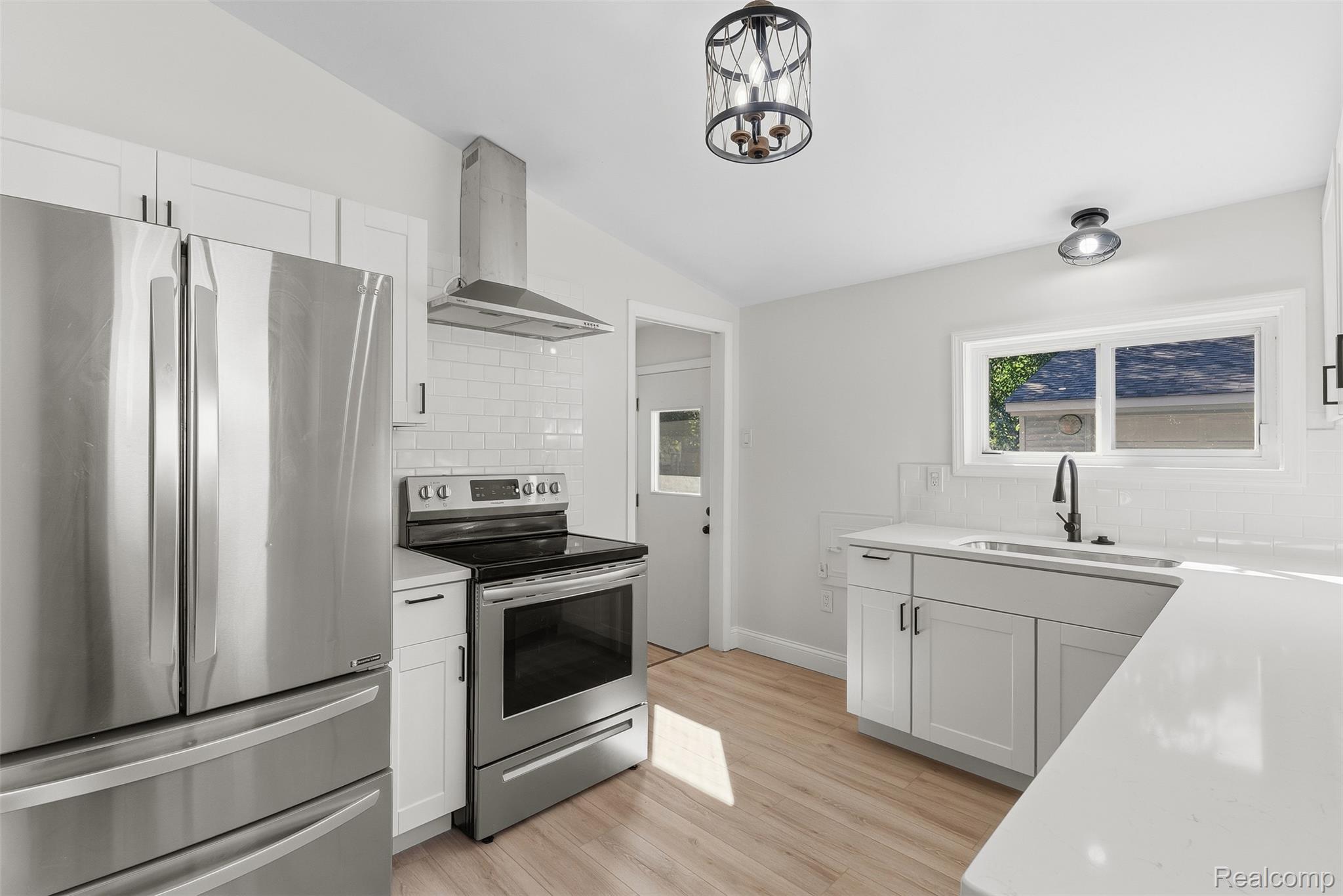 9101 Merriman Road Livonia, MI 48150 - Photo 26 of 41 White cabinetry with black hardware, stainless steel appliances, light wood-finish flooring, white subway tile backsplash, and white countertops