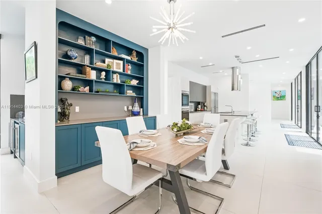 a room with stainless steel appliances lots of white furniture a dining table and chairs