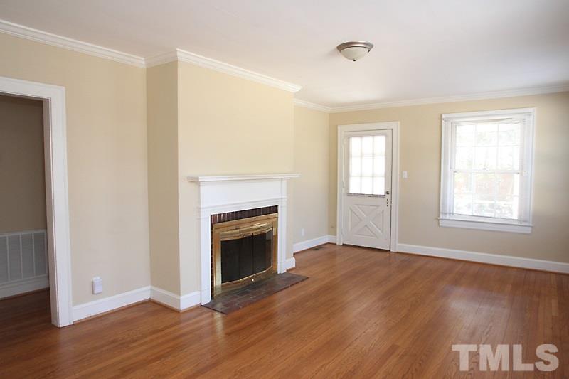 810 Chamberlain Street Raleigh, NC 27607 - Photo 3 of 16 an empty room with wooden floor fireplace and windows