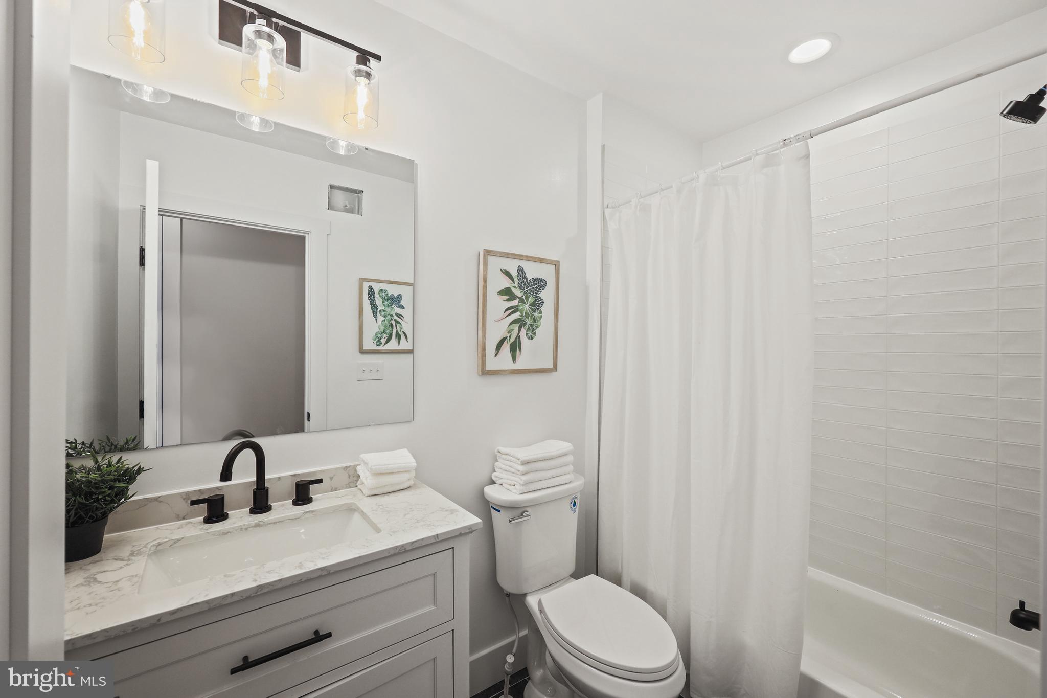 1465 Towson Street Baltimore, MD 21230 - Photo 23 of 39 a bathroom with a sink a toilet and shower curtain