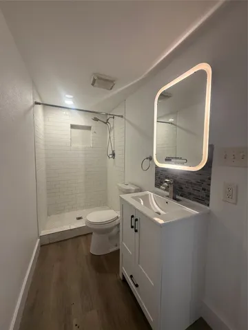 a bathroom with a granite countertop toilet a sink and a mirror