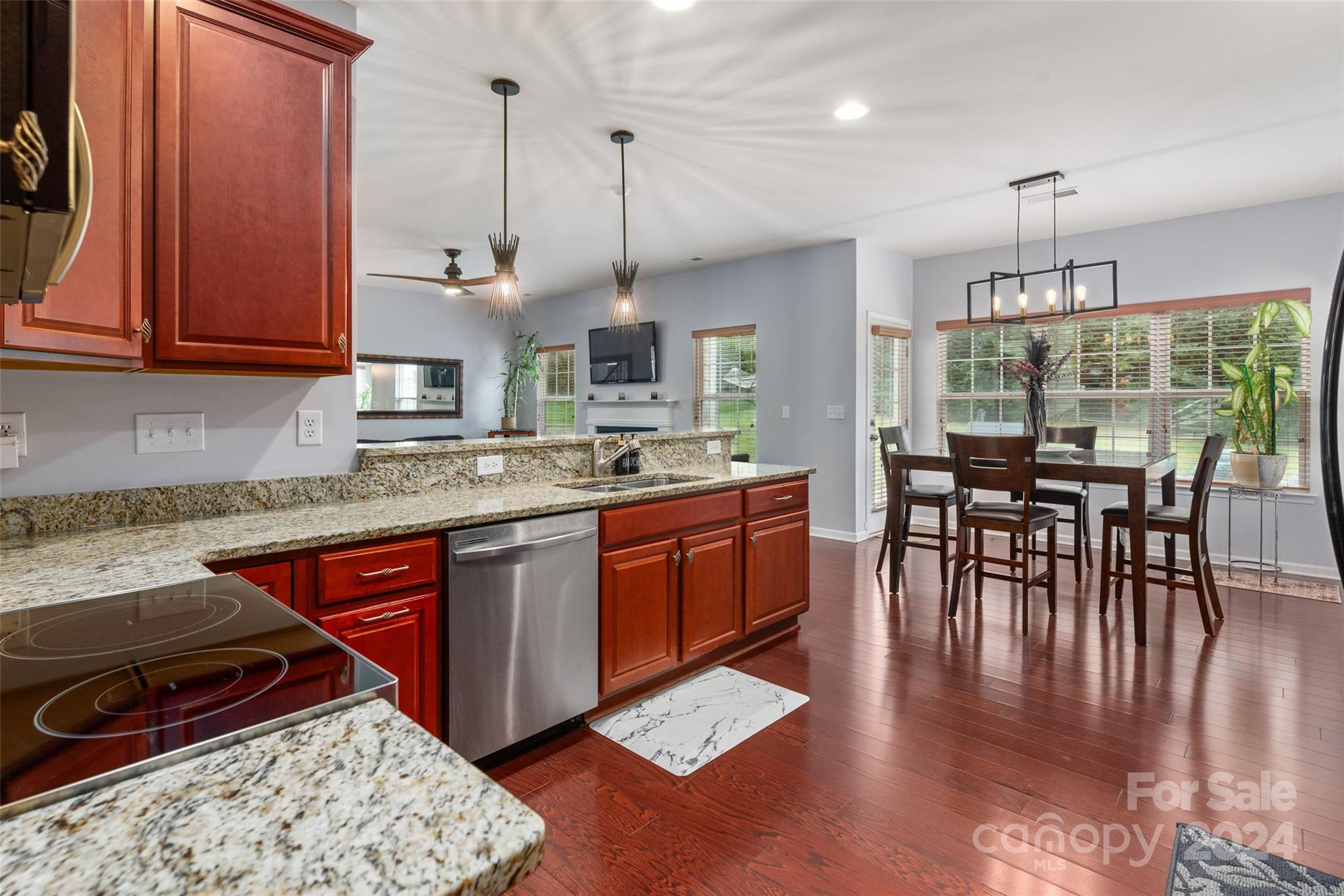 6013 Fox Cub Indian Land, SC 29707 - Photo 11 of 30 a kitchen with stainless steel appliances granite countertop a stove a sink dishwasher a dining table and chairs with wooden floor