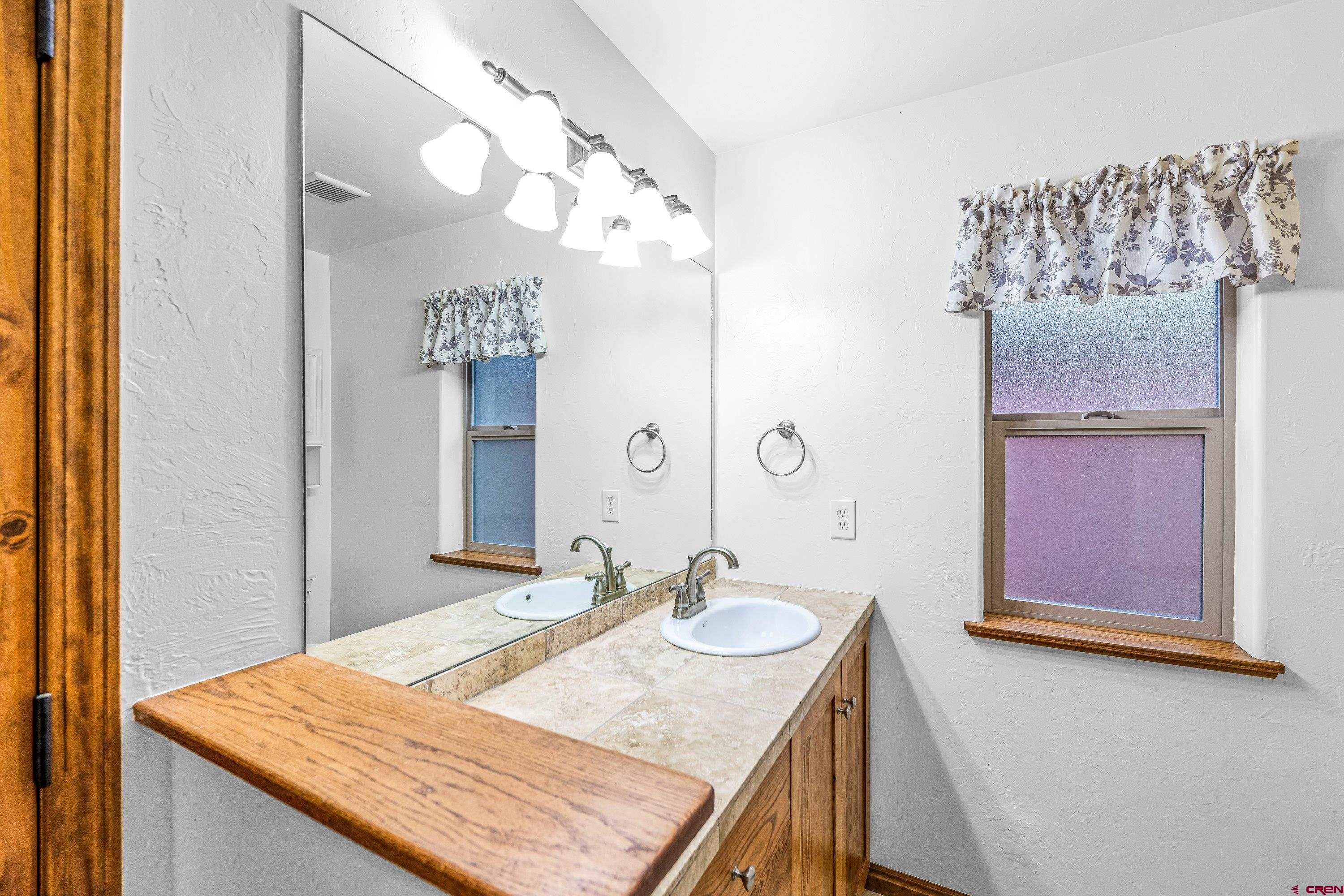 1455 Criterion Street Delta, CO 81416 - Photo 17 of 27 a bathroom with a granite countertop sink a mirror and a shower