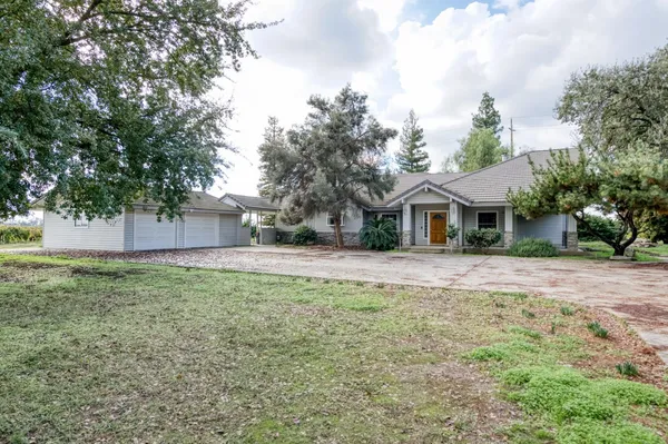 a front view of a house with a yard and trees