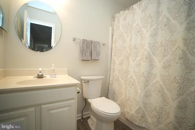 a bathroom with a toilet sink vanity and mirror