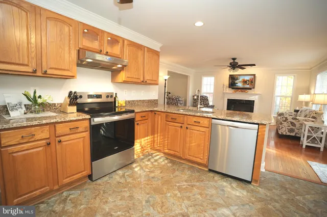 a kitchen with stainless steel appliances granite countertop a stove top oven a sink dishwasher and white cabinets with wooden floor