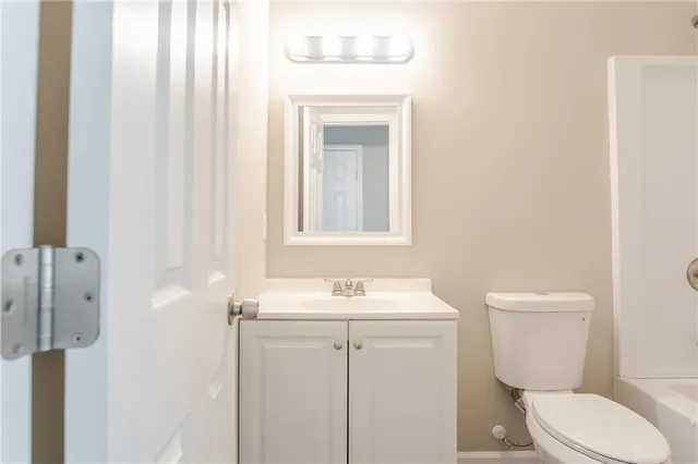 a bathroom with a toilet sink vanity and mirror