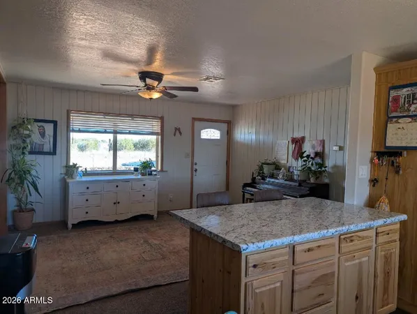 a kitchen with kitchen island a counter top space appliances and a ceiling fan