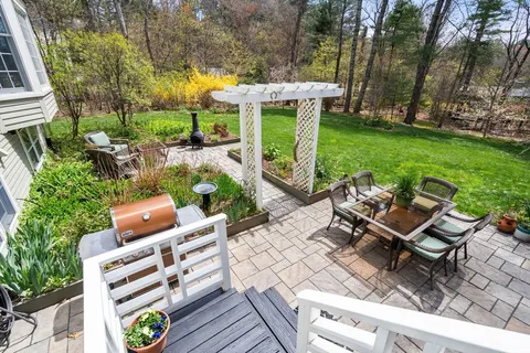 a view of a patio with table and chairs potted plants and a large tree