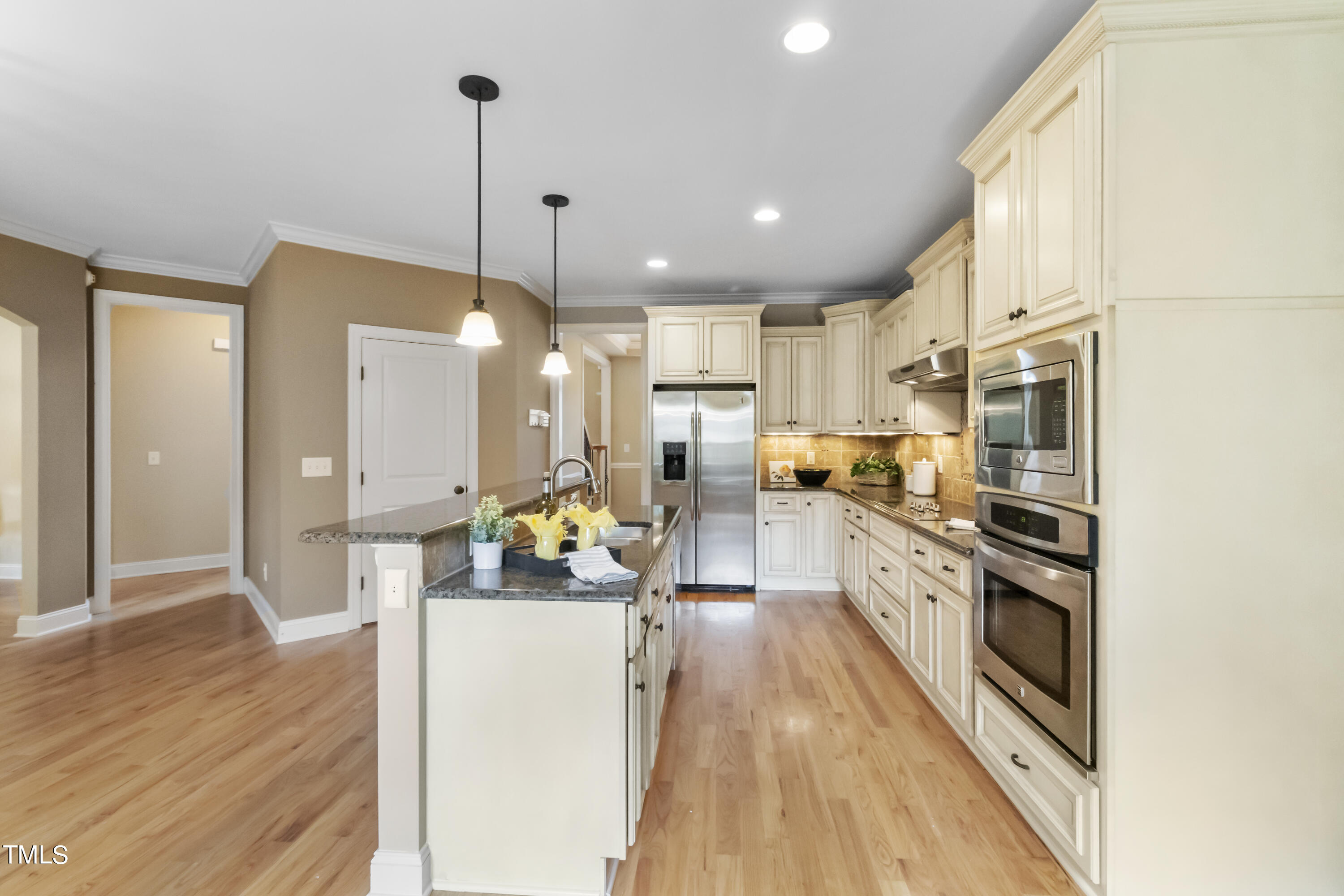 6507 Glendower Road Raleigh, NC 27613 - Photo 7 of 42 a kitchen with stainless steel appliances kitchen island granite countertop a refrigerator a oven a stove and white cabinets with wooden floor