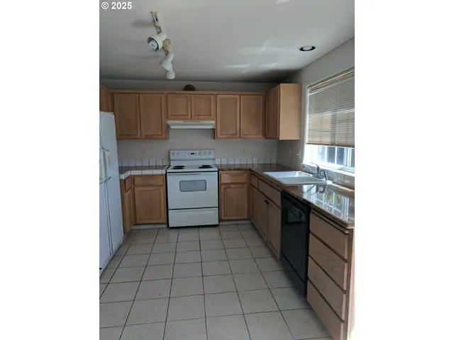 a kitchen with stainless steel appliances granite countertop a sink counter space cabinets and a window