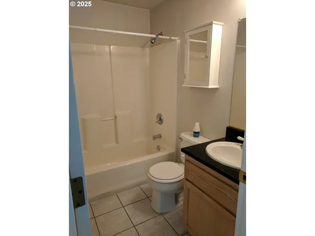 a bathroom with a granite countertop bathtub sink vanity mirror and toilet