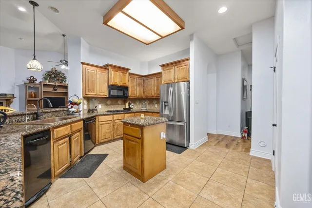 a kitchen with granite countertop a sink a counter space cabinets and stainless steel appliances