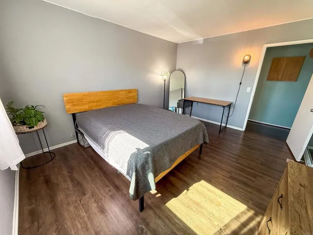 a bedroom with a bed lamp and wooden floor