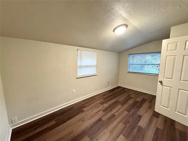 an empty room with wooden floor and window