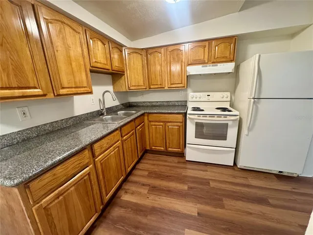 a kitchen with stainless steel appliances granite countertop a sink a stove and a refrigerator