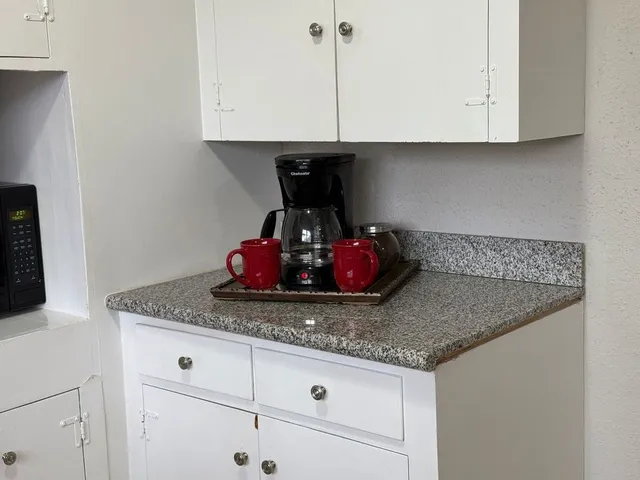 a kitchen with a granite countertop cabinets and white countertops with wooden floor