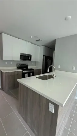 a view of a kitchen with a sink a microwave and cabinets