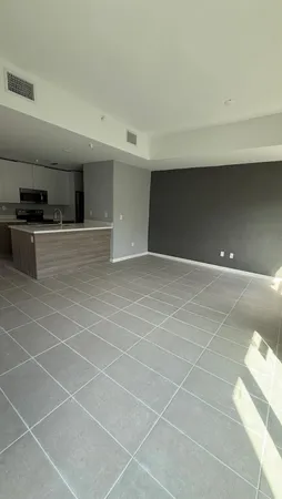 a view of an empty room with kitchen and a window