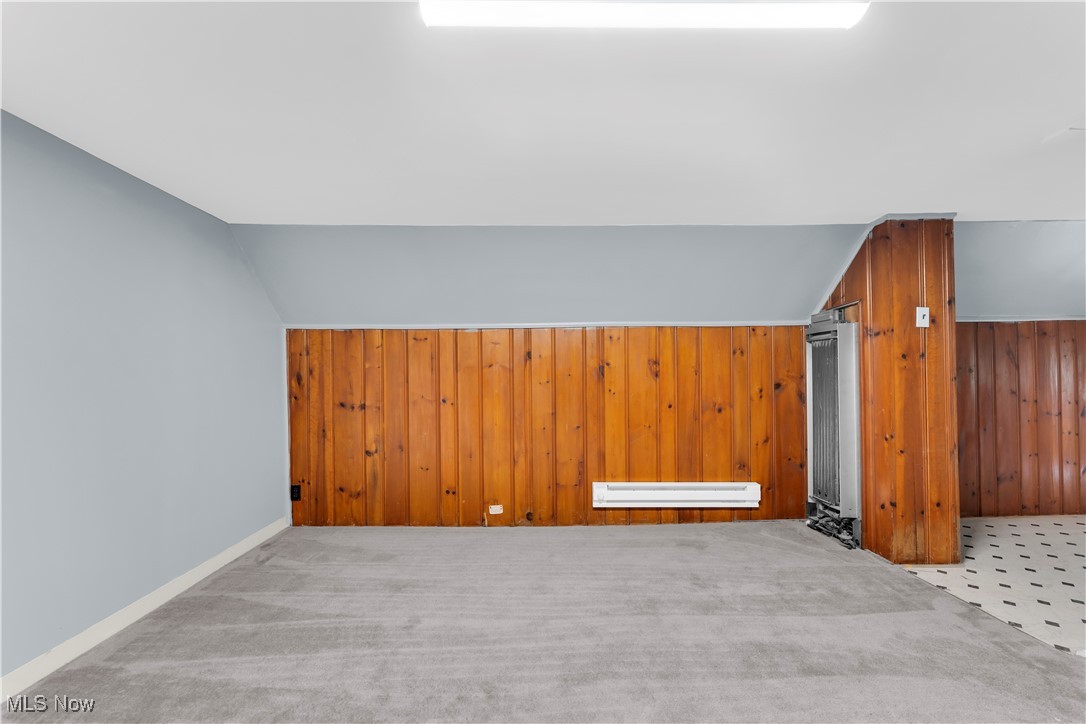 913 Helmsdale Road, Unit 3 Cleveland, OH 44112 - Photo 6 of 19 Additional living space with wood walls, carpet, a baseboard heating unit, and vaulted ceiling
