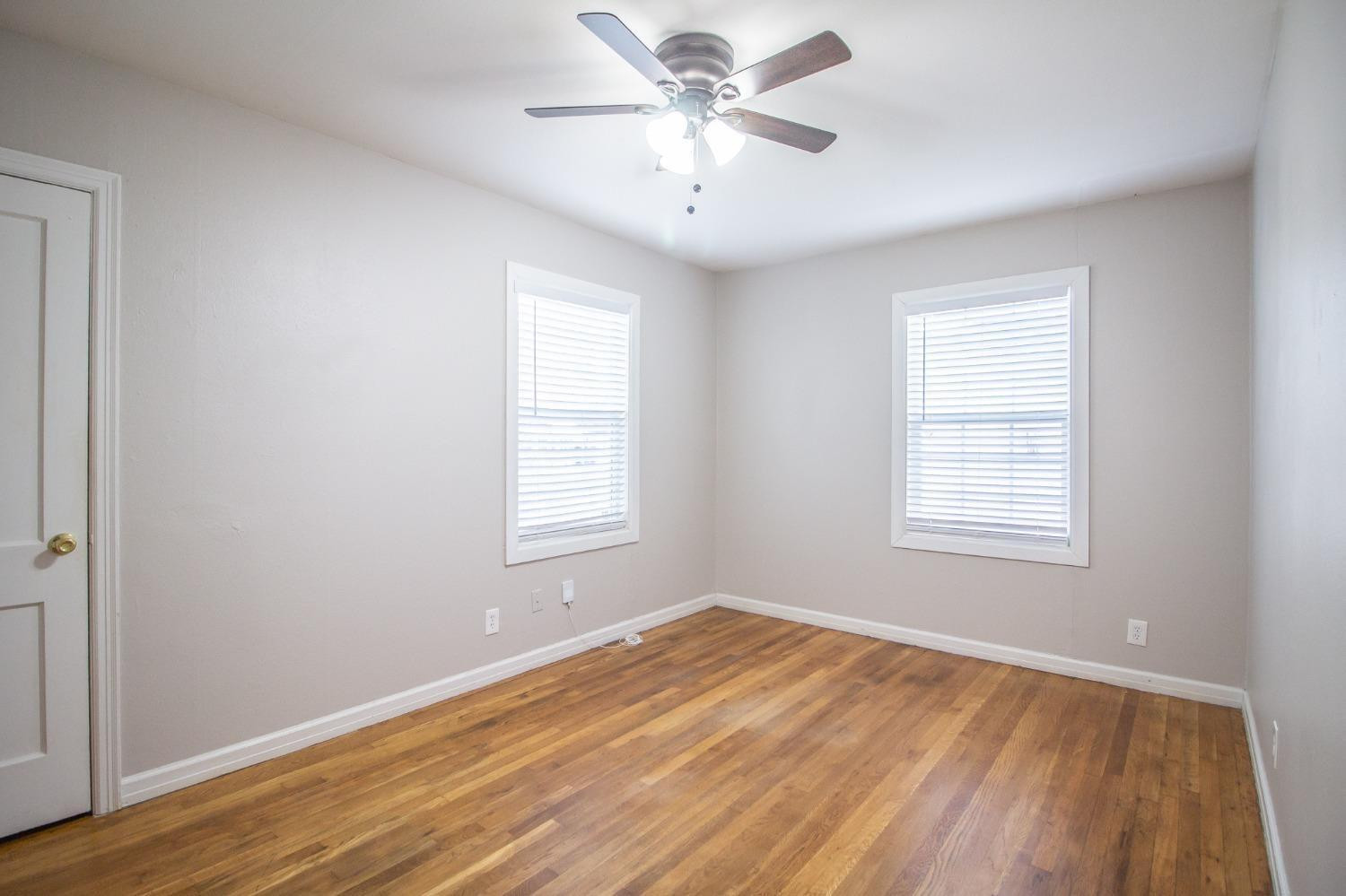 2715 36th Street Lubbock, TX 79413 - Photo 8 of 14 a view of an empty room with wooden floor and a window