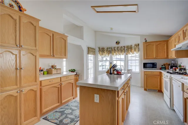 a kitchen with kitchen island granite countertop a sink cabinets stainless steel appliances and a window