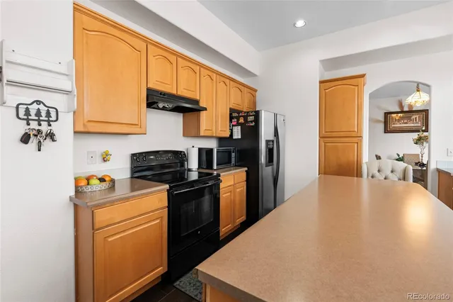 a kitchen with stainless steel appliances granite countertop a stove a refrigerator a sink dishwasher and wooden cabinets with wooden floor