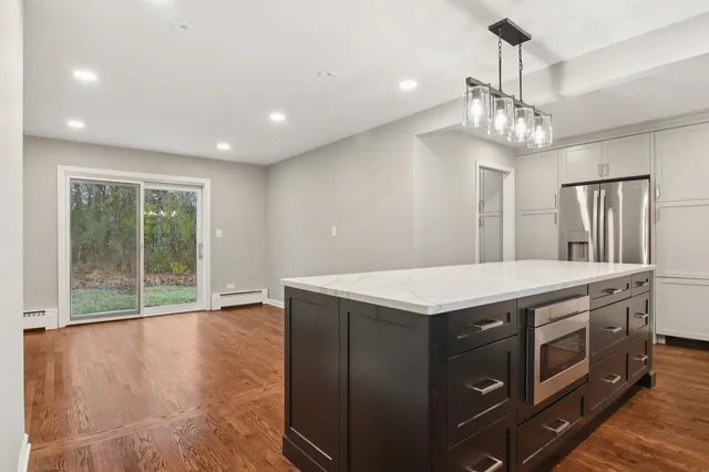 a kitchen that has a lot of stainless steel appliances wooden floor and a chandelier