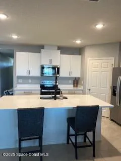 a kitchen with stainless steel appliances granite countertop a sink a stove a refrigerator cabinets and a dining table with wooden floor