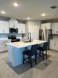 a kitchen with stainless steel appliances a stove a sink a microwave a refrigerator and cabinets