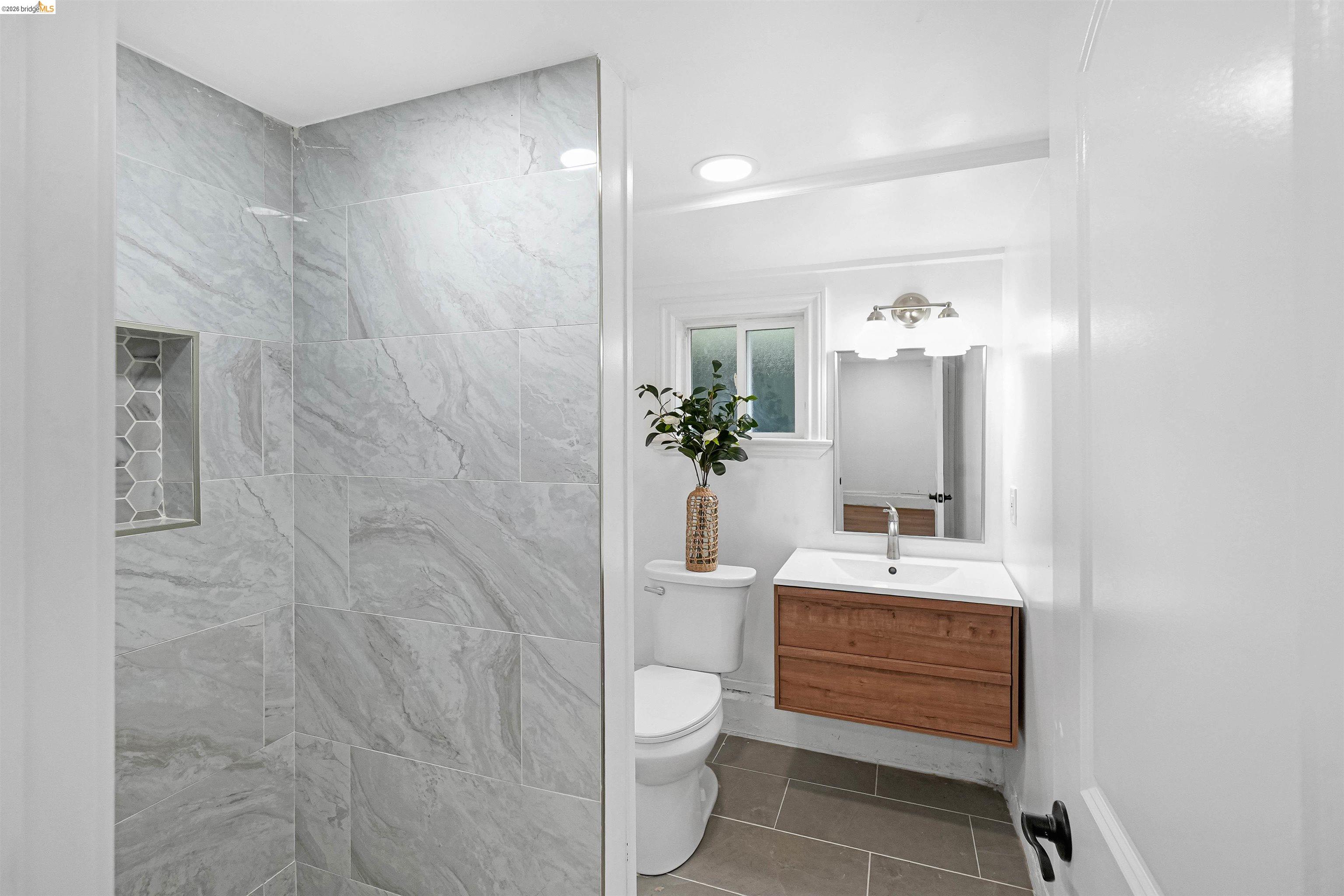 1812 Woolsey Street Berkeley, CA 94703 - Photo 41 of 48 Contemporary bathroom showcasing a floating wood-finish vanity with a rectangular sink, brushed nickel faucet, and coordinating wall-mounted light fixture