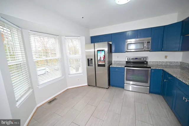 a kitchen with stainless steel appliances granite countertop a refrigerator and a stove top oven