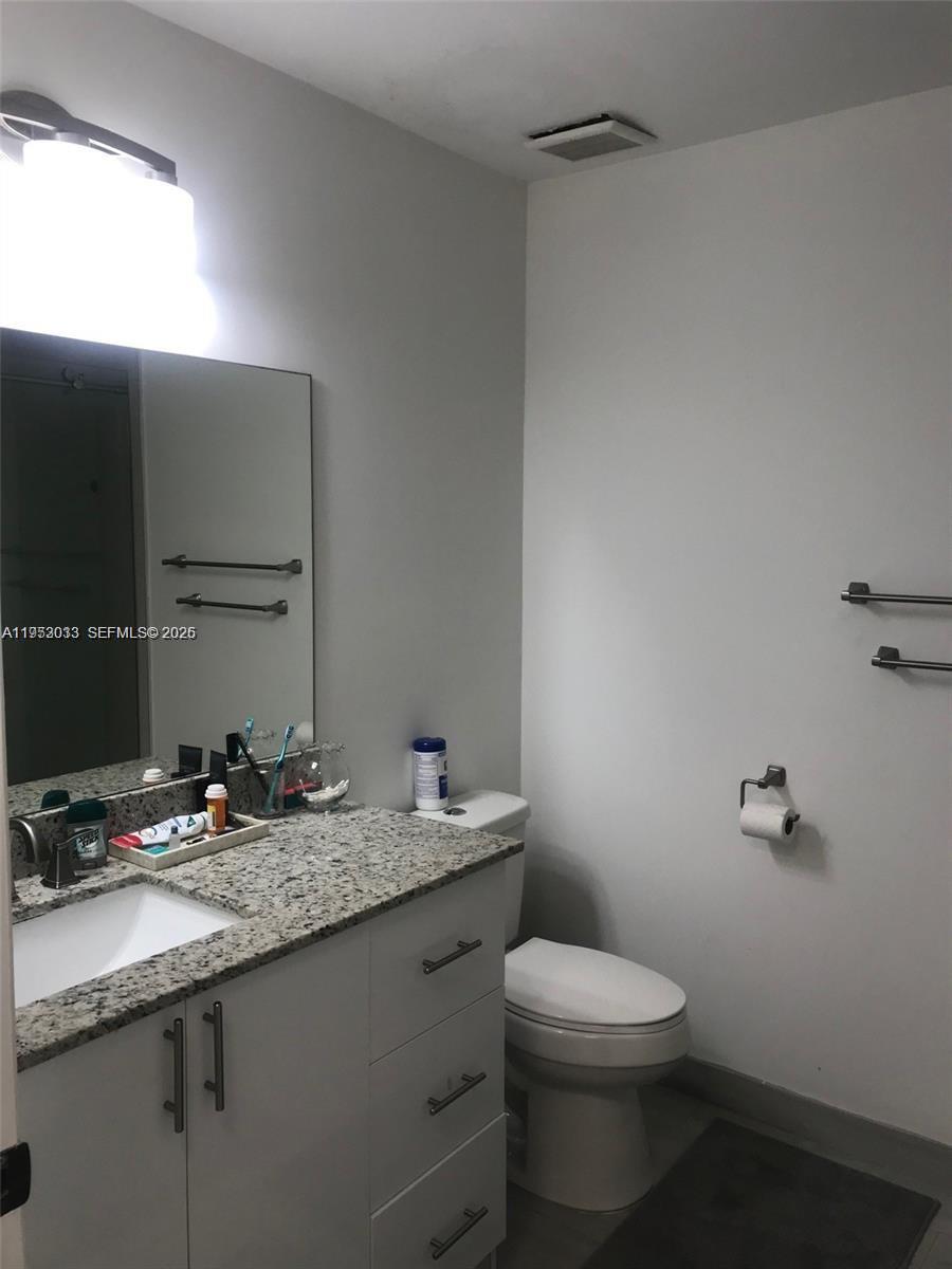 14621 Balgowan Road, Unit 1023 Miami Lakes, FL 33016 - Photo 8 of 21 a bathroom with a granite countertop sink a toilet and a mirror