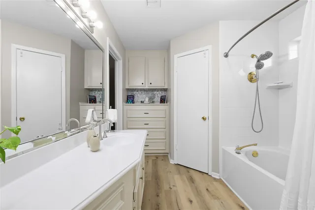 a bathroom with a granite countertop sink a mirror a bathtub and shower