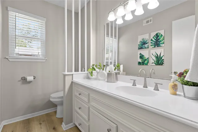 a bathroom with a granite countertop sink a large mirror a toilet and a window