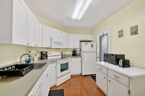 a kitchen with white cabinets and white appliances