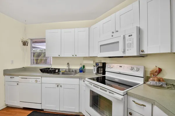 a kitchen with granite countertop white cabinets and white appliances