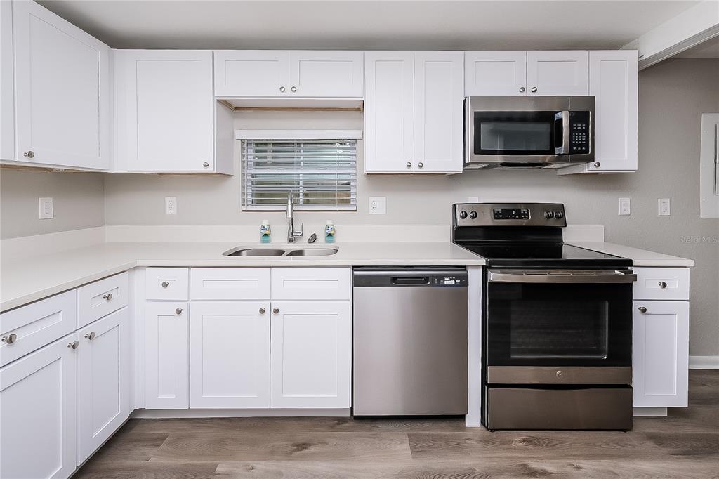 7145 Pinewood Drive New Port Richey, FL 34652 - Photo 6 of 16 a kitchen with white cabinets and stainless steel appliances