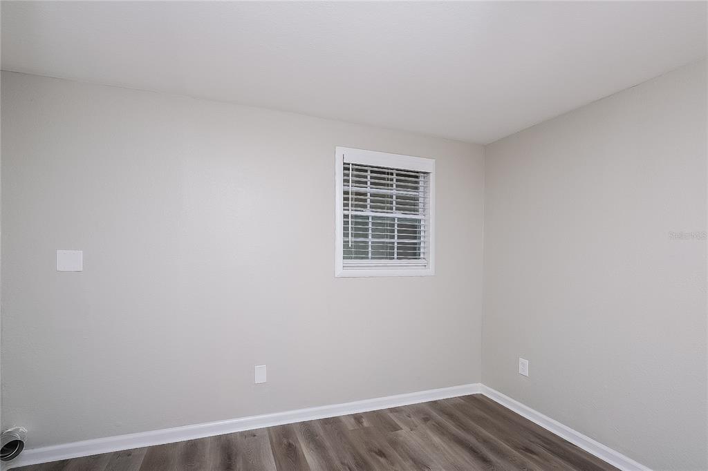 7145 Pinewood Drive New Port Richey, FL 34652 - Photo 9 of 16 a view of an empty room with wooden floor and a window