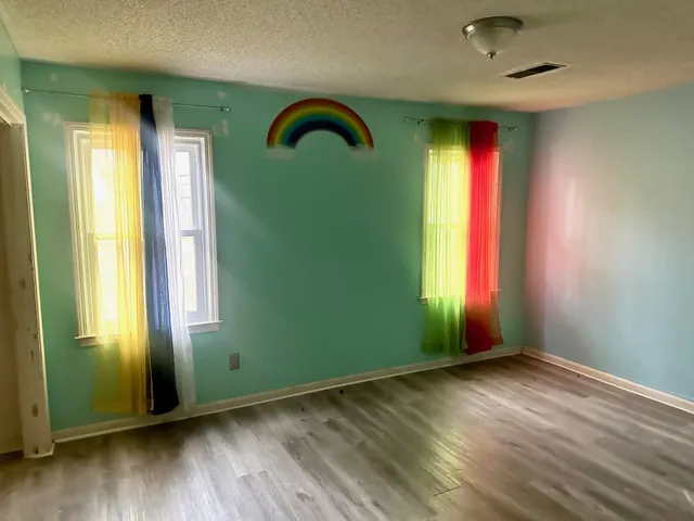 an empty room with wooden floor and windows
