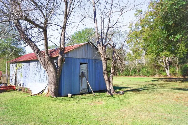a view of backyard of house with wooden fence and large trees