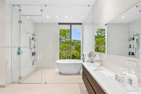 a bathroom with a double vanity sink a large mirror and a bathtub