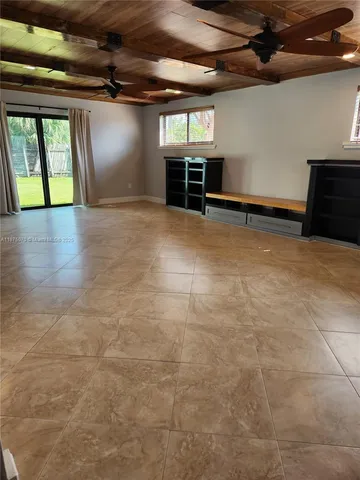 an empty room with wooden floor and kitchen view