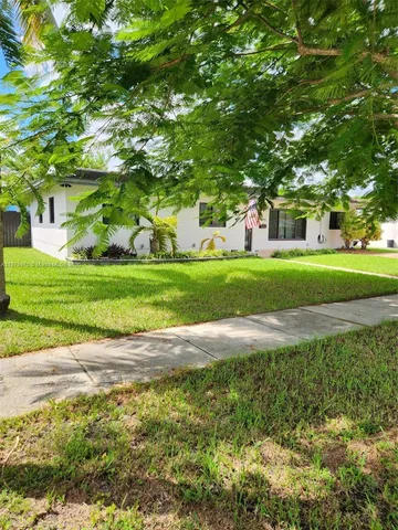 a view of a house with a big yard and large trees